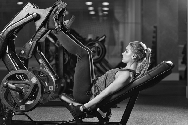 Sportive woman using weights press machine for legs. Gym. - Zdjęcie, obraz