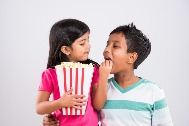 διαφορετικές διαθέσεις, ενώ μικρό ινδικό κορίτσι παιδί και το αγόρι που τρώει ποπ κορν - Φωτογραφία, εικόνα