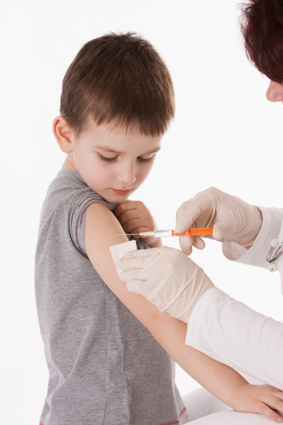 Doctor giving a child injection in arm on isolated image. - 写真・画像