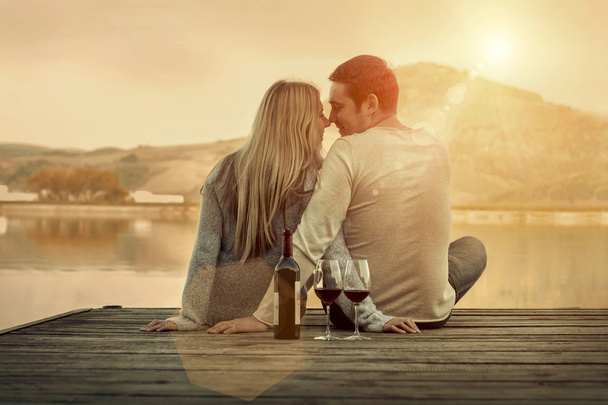 Paar zittend op de pier met rode wijn - Foto, afbeelding