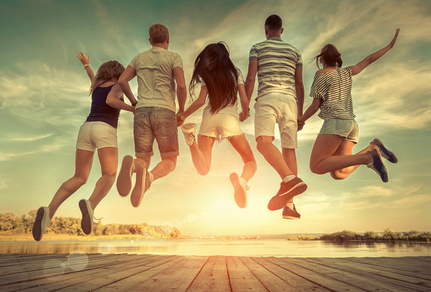 Gruppe von Freunden springt im Sonnenlicht auf die Seebrücke. - Foto, Bild