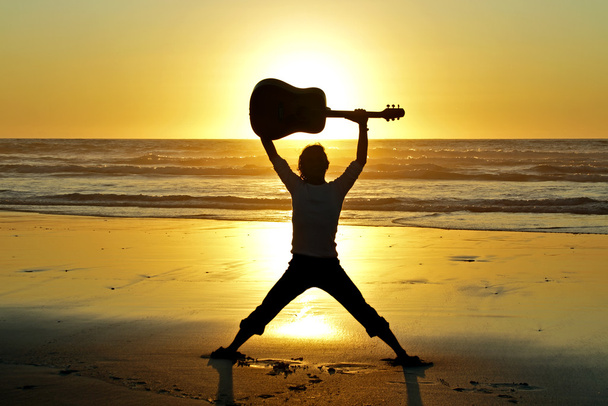Guitar player on the beach at sunset - 写真・画像