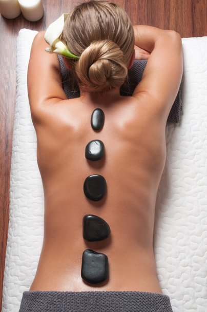 Stone massage. Beautiful woman getting spa hot stones massage in spa salon. - Valokuva, kuva
