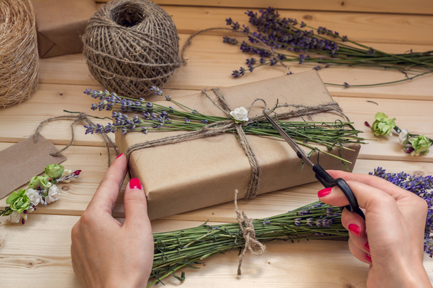 Woman decorating gift box on wooden background, view from above - 写真・画像