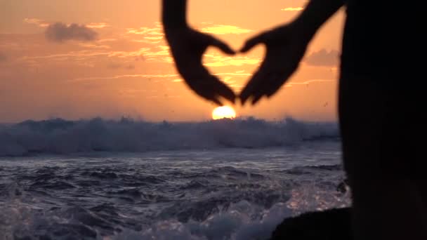 SLOW MOTION: Young woman capturing beautiful golden sky with heart shaped hands - Footage, Video