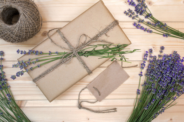 Gift box decorated  branch of lavender on wooden background, view from above - Fotó, kép