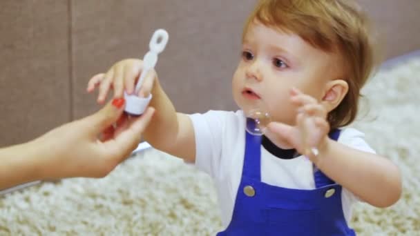 Child in room enjoys soap bubbles mom - Filmati, video