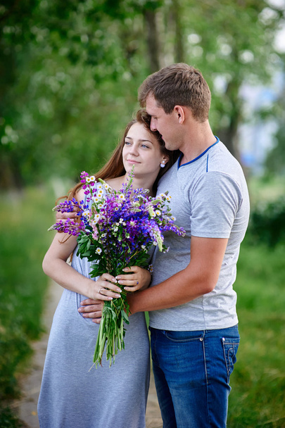 couple in love with bouquet are embracing in park - Foto, immagini