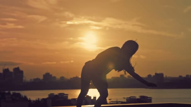 Young attractive girl with flowing hair dancing movements of Kupwara at sunset silhouette - Video, Çekim