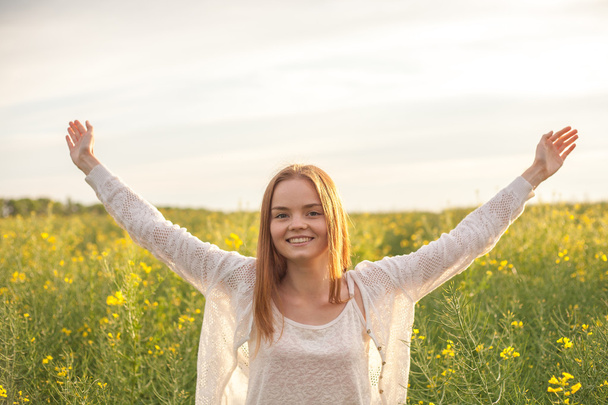 woman with open arms in the green rapeseed field at the morning. - Photo, Image