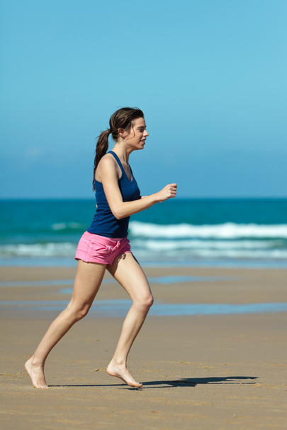 Girl running on the beach in barefoot - Foto, afbeelding