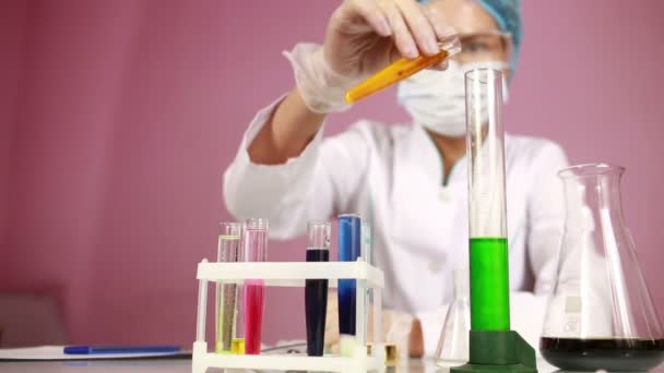 Ženské chemik porovnávání zkumavek s chemikáliemi. ochranné brýle - Záběry, video