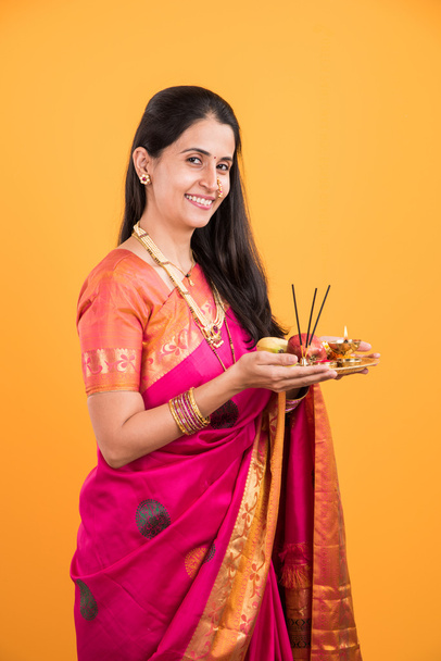 Mulher indiana realizando puja, menina indiana com pooja thali ou puja thali, retrato de uma bela jovem com pooja thali, isolado sobre fundo amarelo
 - Foto, Imagem