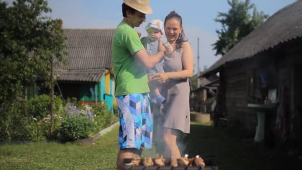 The kids father and mother cook meat on the fire. Barbecue is almost ready - Materiał filmowy, wideo