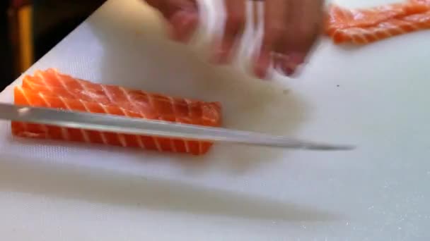 Sushi Chef Slicing a Salmon Steak Nigiri Style A sushi-man slicing a salmon steak with his Japanese knife. Preparing sushi nigiri fish. Japanese cuisine recipes. Professional chef with kitchen knives - Footage, Video