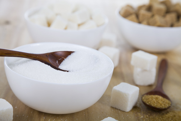 Ζάχαρη από ζαχαροκάλαμο και το λευκό σε ένα λευκό κύπελλα  - Φωτογραφία, εικόνα