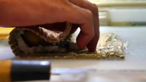 Suši šéfkuchař připravuje lososa broskvový Futomaki Roll. Suši muž vaření losos, avokádo, broskev, krevety a mlíčí sushi rohlíky. Japonská kuchyně recepty. Profesionální kuchař s kuchyňské nástroje. - Záběry, video