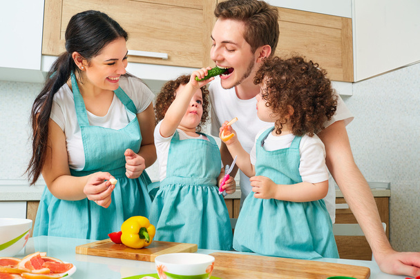 Twins girl with her parents in the kitchen eating buns. A happy  - Фото, зображення