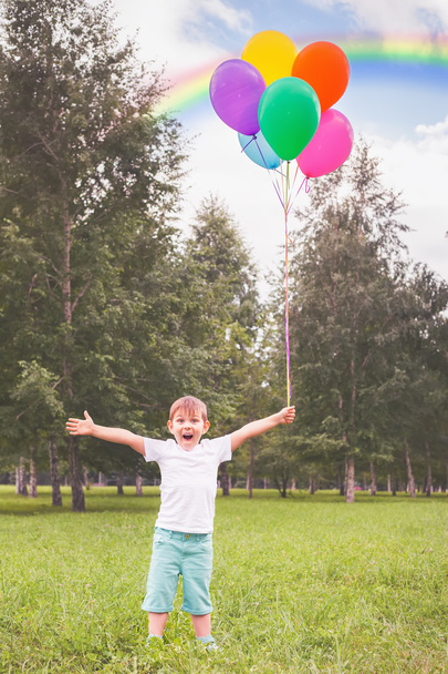Happy child with balloons and beautiful rainbow outdoor - Fotoğraf, Görsel