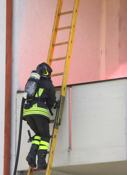 Pompiere con bombola di ossigeno che sale su una scala di legno
 - Foto, immagini