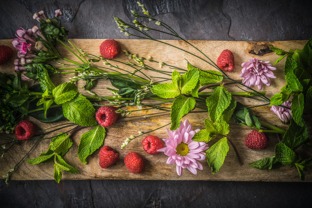 Flowers  , raspberries and mint on the wooden board  top view - Zdjęcie, obraz