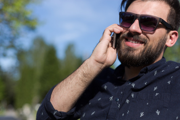 Young bearded man talking on smartphone  - Fotó, kép