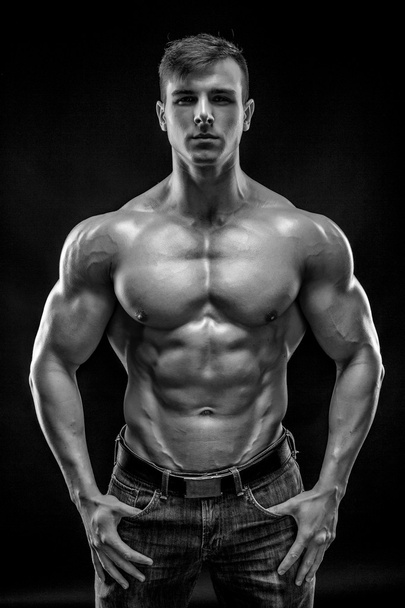 Muscular bodybuilder guy doing posing over black background - Foto, Imagen