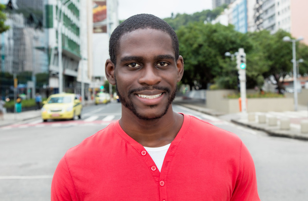 Смеющийся африканский американец в красной рубашке в городе
 - Фото, изображение