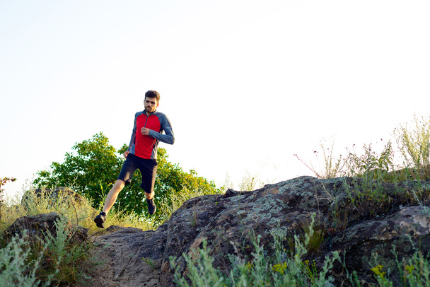 Young Sportsman Running on the Rocky Mountain Trai in the Evening. Active Lifestyle - Photo, Image