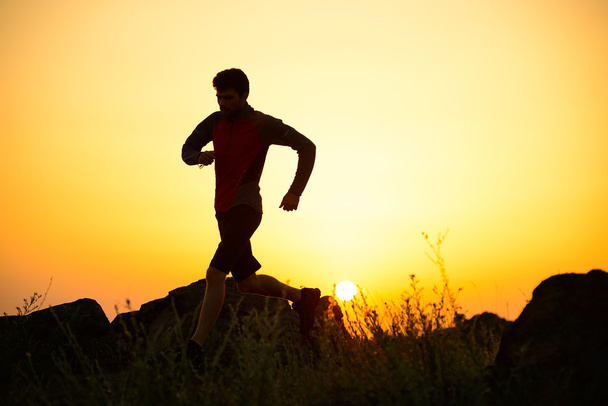 Jeune sportif Running on the Rocky Mountain Trail at Sunset. Mode de vie actif
 - Photo, image