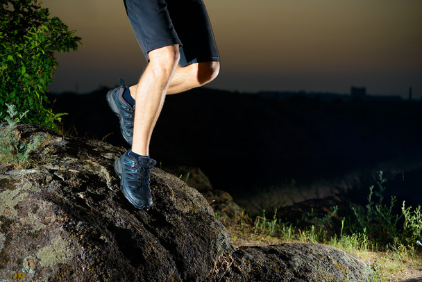 Gros plan sur les jambes d'un sportif qui court sur le sentier des Rocheuses la nuit. Mode de vie actif
 - Photo, image