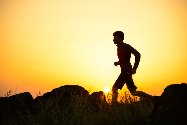 Fiatal sportoló fut a Rocky Mountain Trail a naplemente. Aktív életmód - Fotó, kép