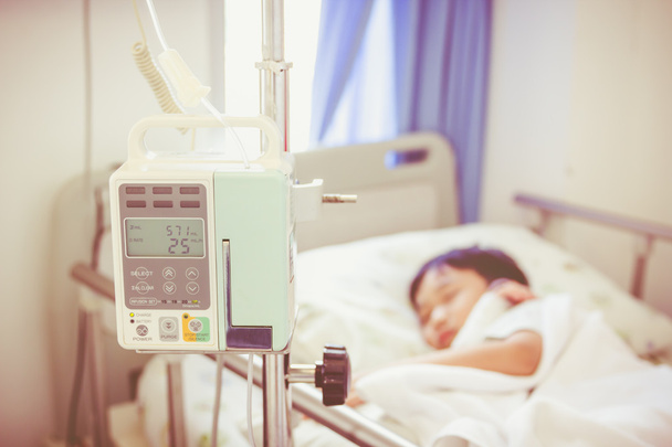 Asian boy lying on sickbed with infusion pump intravenous IV drip - Photo, Image