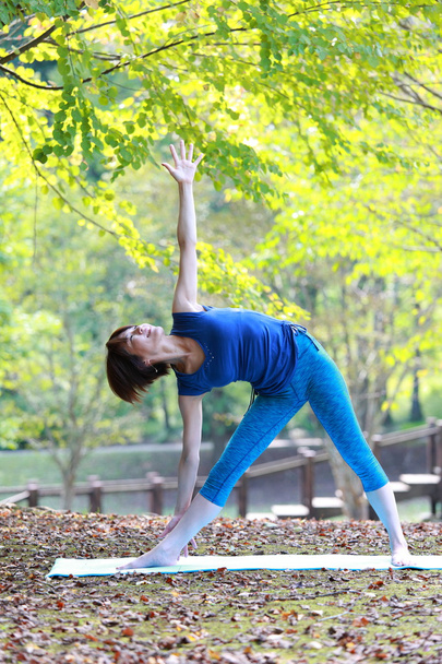 Japanese woman outside doing yoga triangle pose - Zdjęcie, obraz