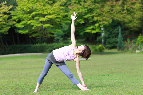 Japanese woman outside doing yoga triangle pose - Foto, Imagem