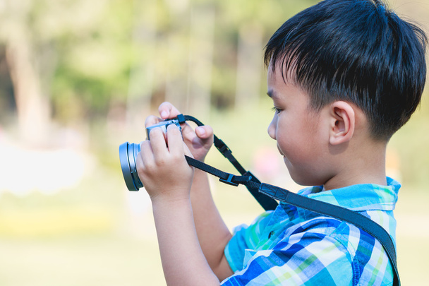 Boy taking photo by camera, on blurred nature background.  - Foto, imagen