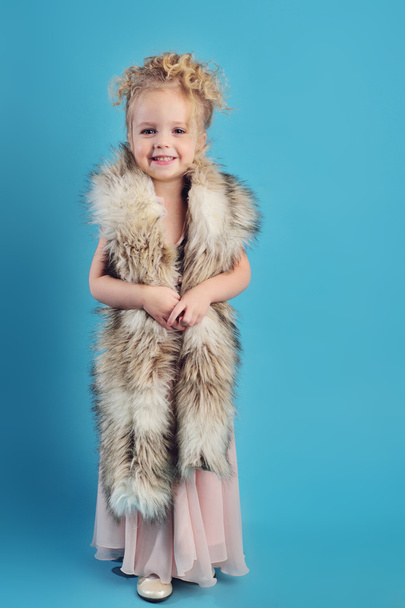 little girl in a long dress and a fur coat - Фото, изображение