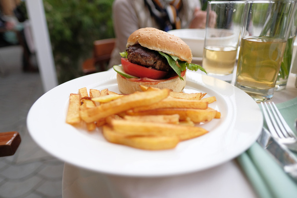 Гамбургер и картошка фри за столом ресторана
 - Фото, изображение