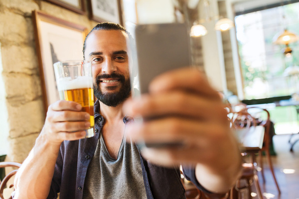 man with smartphone drinking beer  - Photo, Image
