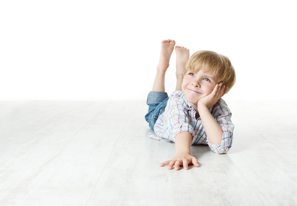 Thinking smiling little boy lying down on floor - Foto, Bild
