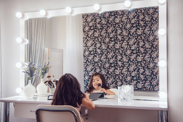Little girl in front of the mirror doing her makeup - Фото, изображение