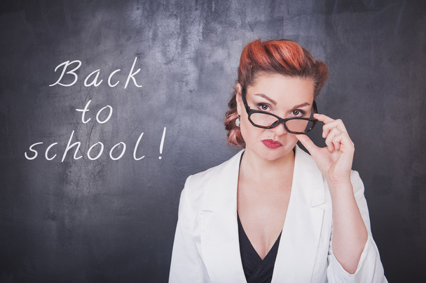 Serious teacher in glasses on blackboard background - Photo, Image