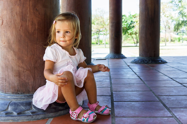 little girl sitting near the column - Foto, afbeelding
