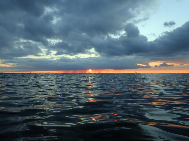 Sun dips below clouds as it lowers to the Pacific ocean - Φωτογραφία, εικόνα