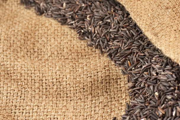 abstrakte Nahaufnahme eines flachen Teils roher Reisbeeren über zerriebenem Ackersackhintergrund - Foto, Bild