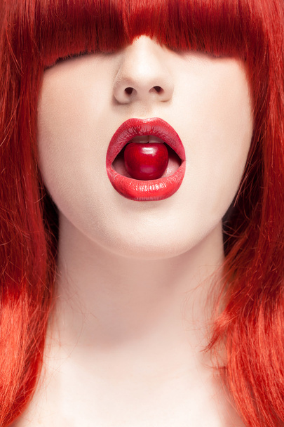 Vrouw met rode pruik bijten sexy in mond een kers - Foto, afbeelding