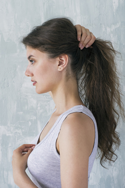 Side view of brunette with hair in hand making tail - Valokuva, kuva