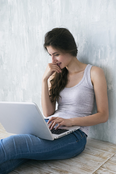 Young woman slightly smiling at laptop screen - Photo, Image