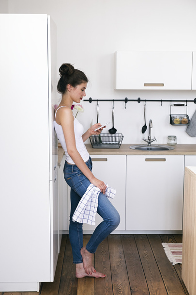 Barefoot girl using cell phone in kitchen - Foto, immagini