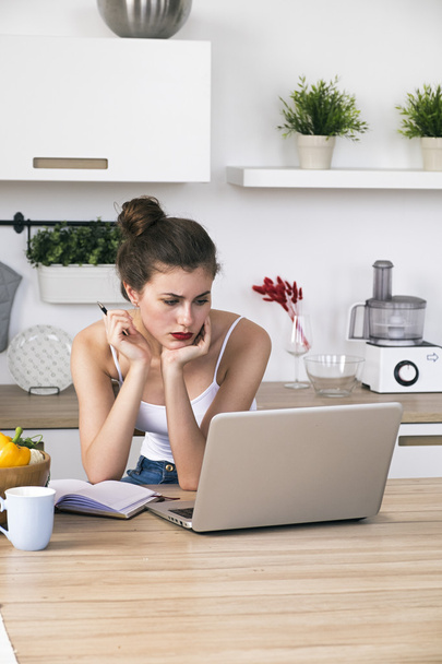 Portrait of housewife at table with laptop in kitchen - Photo, Image